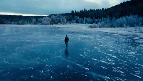 Indre-Fosen,-Trondelag-County,-Norway---A-Man-Strolling-Across-the-Icy-Surface-of-Omundvatnet---Orbit-Drone-Shot