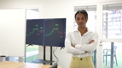 Schwarzafrikanische-Geschäftsfrau-Blickt-In-Die-Kamera-Mit-Einer-Handelsansichtsgrafik-Im-Hintergrund-Und-Ernstem-Gesichtsausdruck