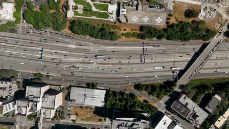 Lowering-top-down-drone-shot-of-traffic-driving-through-Seattle's-downtown-freeways