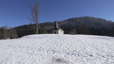 Wide-shot-of-the-Chapelle-St-Florent-on-top-of-a-snow-covered-hilltop-near-Longemer-lake