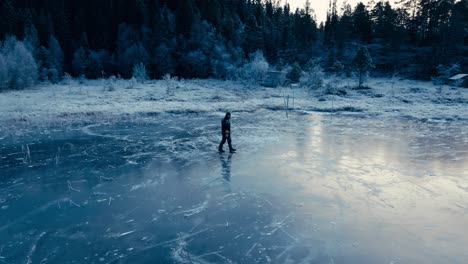 Indre-Fosen,-Trondelag-County,-Norway---A-Man-Walking-on-the-Lake's-Snow-covered-Surface-of-Omundvatnet---Orbit-Drone-Shot