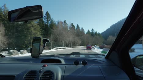 Car-driving-on-turning-road-through-the-french-Vosges-mountains-in-France,-winter-landscape