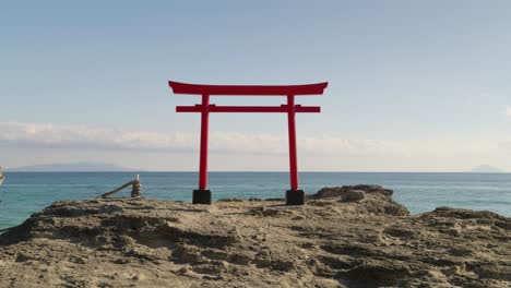 Calm-and-relaxing-scenery-with-Japanese-Torii-gate-against-ocean-on-top-of-rock