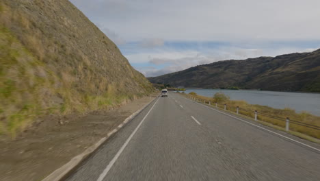 POV-From-Car-Driving-In-The-Road-Passing-By-The-Clyde-Dam-In-Clyde,-Otago,-New-Zealand