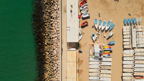 Drone-top-down-shot-capturing-beach-filled-with-boats-by-green-sea