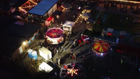 Illuminated-Christmas-funfair-festival-in-neighbourhood-car-park-at-night-aerial-view