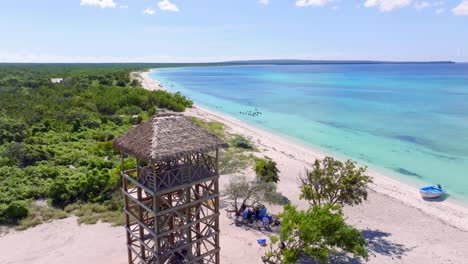 Wooden-observation-tower-on-exotic-tropical-sand-beach,-aerial-forward