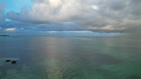 Drone-view-in-Belize-flying-over-caribbean-dark-and-light-blue-sea-shallow-water-coral-reef-and-and-a-flying-bird