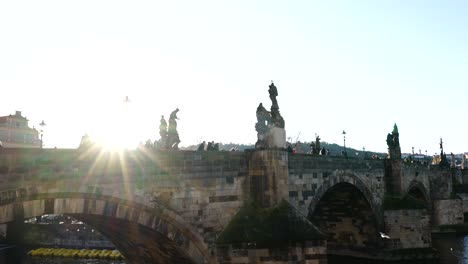 Crowded-stone-arch-Charles-bridge-with-statues-during-bright-sunset
