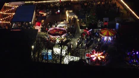 Variety-Illuminated-Christmas-fairground-festival-in-neighbourhood-car-park-at-night-aerial-view