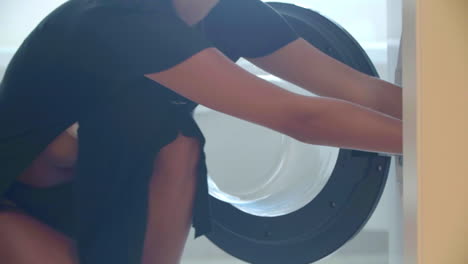 Slow-motion-footage-captures-a-seductive-woman-in-a-black-dress-handling-laundry-as-it-emerges-from-the-washing-machine