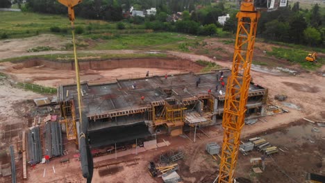 Aerial-view-capturing-the-movement-of-a-crane,-transporting-construction-materials-behind