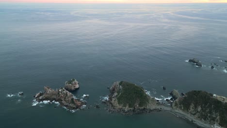 Aerial-Drone-Fly-Above-Lonely-Islets-around-Blue-Ocean-at-Barra-de-Navidad-Sea,-Sunset-Skyline-in-Jalisco-Mexico