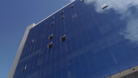 Panoramic-view-of-a-mirrored-building-reflecting-the-blue-sky-with-clouds