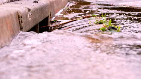 Nahaufnahme-Des-Regenwasserabflusses,-Der-über-Die-Betonrinne-In-Den-Straßenabfluss-Fließt