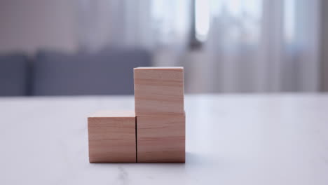 Taking-a-close-up-shot-of-an-individual-stacking-wooden-blocks-on-top-of-each-other-on-a-table