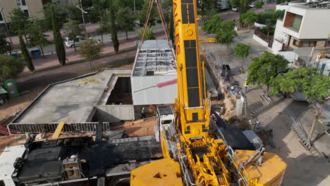 Big-yellow-crane-transporting-pre-fabricated-modular-house-to-construction-site