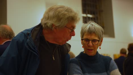 Grey-haired-senior-couple-with-black-glasses-nodding-and-talking