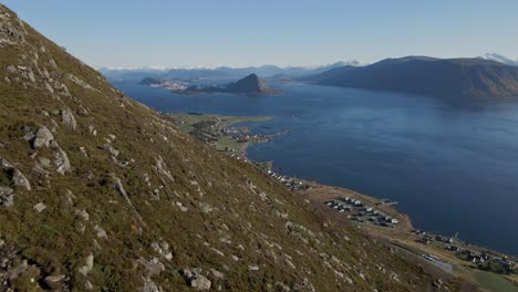 Aerial-tilt-up-shot-of-hiker-group-on-rocky-mountain-in-Norway-with-Fjord-in-the-valley