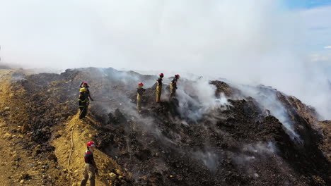 Drohnenaufnahme-Von-Feuerwehrleuten-Aus-Der-Luft,-Die-Einen-Waldbrand-Inmitten-Aufsteigenden-Rauchs-Löschen,-Sonniger-Tag,-In-Der-Dominikanischen-Republik