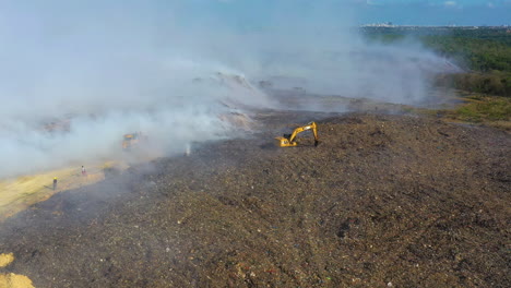 Aerial,-tracking,-drone-shot-of-the-firemen-using-a-Digger-to-fight-a-wildfire,-smoke-rising-in-destroyed-nature,-sunny-day,-in-the-Amazon-jungle,-Brazil,-South-America