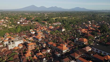 Establishing-shot-of-Ubud-downtown-with-traditional-Balinese-houses,-villas,-dense-palm-trees-and-volcanoes-at-the-background,-Bali,-Indonesia