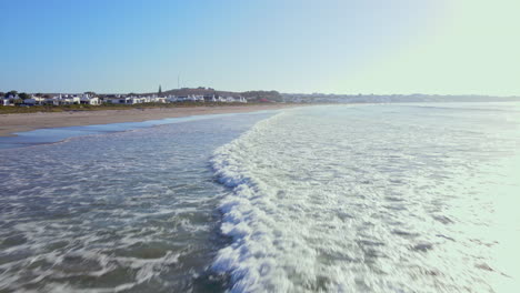 Low-drone-flight-over-waves-rolling-on-to-long-stretch-of-Paternoster-beach