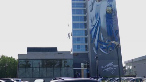 Eine-Bewegende-Szene,-Die-Das-Verlassen-Des-Parkplatzes-Einfängt,-Wobei-Das-Markante-Maradona-Wandgemälde-Die-Hintergrundlandschaft-Dominiert