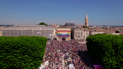 Überfüllte-Straßen-Mit-Lebhafter-Gay-Pride-Parade,-Geschmückt-Mit-Einer-Riesigen-Regenbogenfahne