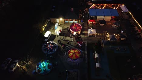 Illuminated-Christmas-amusement-park-in-neighbourhood-car-park-at-night-aerial-view
