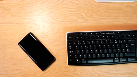 Smartphone-Und-Tastatur-Auf-Holzschreibtisch