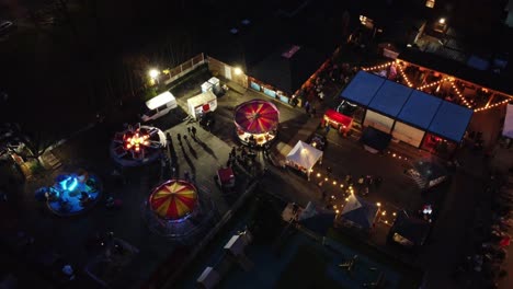 Beleuchteter-Weihnachts-Vergnügungspark-Auf-Dem-Parkplatz-Des-Nachbarschaftskneipens-Bei-Nacht,-Luftaufnahme