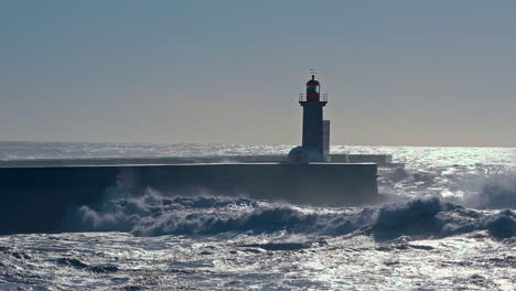 Zoom-out-shot-on-crashing-waves-of-Atlantic-Ocean-and-Lighthouse-in-Porto-at-sunset---slow-motion-wide-shot