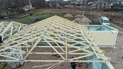 Timber-truss-roof-frame-installed-on-a-new-home-project---pullback-aerial-reveal