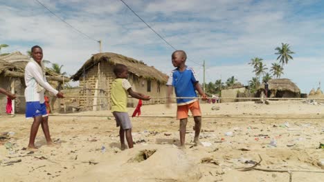 Kleine-Jungen-Ziehen-Fischernetze-Am-Seil-Zum-Sandstrand-In-Moree,-Ghana