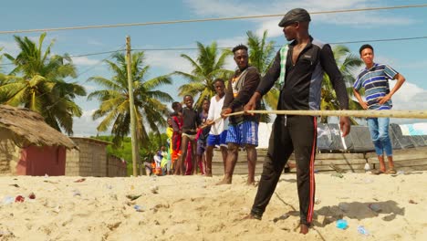 Close-view-of-young-men-pulling-fishing-net-to-beach-in-Moree,-Ghana