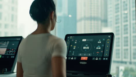 Fit-asian-female-jogger-trains-on-a-treadmill-in-Technogym-commercial-gym