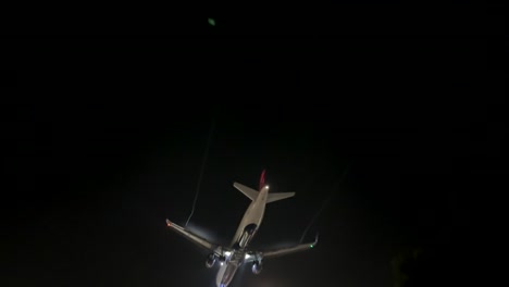 Delta-Flugzeug-Von-Unten,-Das-Am-Dunklen-Nachthimmel-Vorbeifliegt,-Während-Es-Zur-Landung-Absteigt