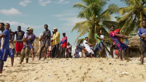 Young-men-pull-net-out-of-sea-to-beach-in-Moree-fishing-village,-Ghana