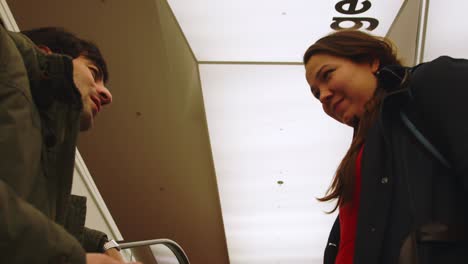 Handsome-boy-and-girl-on-modern-escalator-during-first-date-interior
