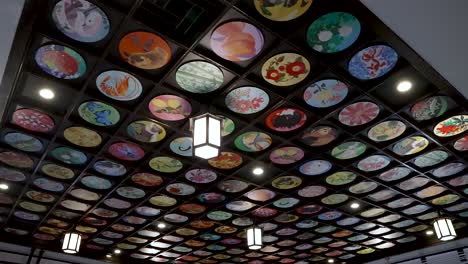 Looking-Up-At-Ceiling-Of-Gokurakubashi-Station-With-Colourful-Round-Artistic-Plates