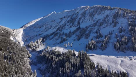 Aerial-view-showing-beautiful-snowy-mountain-panorama-against-blue-sky-in-Switzerland