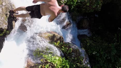 Man-on-rock-visiting-crashing-waterfall-of-River-San-Rafael-during-sunny-day---Aerial-view