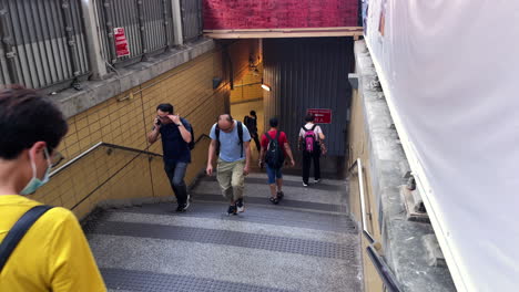 People-walk-down-the-stairs-to-a-subway-station-in-Hong-Kong,-China