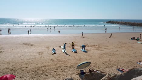 Surf-coaching-at-Praia-do-Tarquínio-Paraíso-beach-during-autumn-in-the-waves-of-Atlantic-Ocean,-Costa-da-Caparica,-Portugal