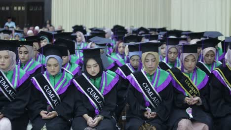 A-group-of-female-graduates-sit-and-pray-for-their-success-on-graduation-day