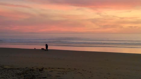 Unbekanntes-Paar-Mit-Hund,-Das-Während-Des-Goldenen-Sonnenuntergangs-In-Der-Abenddämmerung-In-Playa-Del-Carmen,-Einem-Küstenort-In-Mexiko,-Auf-Dem-Strandsand-Spaziert