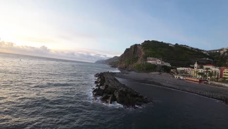 Close-up-of-a-coastal-jetty-and-the-shoreline-with-buildings-in-Ponta-do-Sol,-Madeira