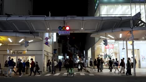 Japanese-people-passing-crowded-zebra-crossing,-street-scene-at-night-Kyoto-Japan
