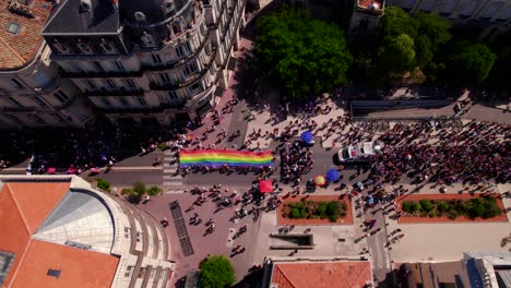 Aerial-view-of-long-rainbow-flag-held-by-crowd-of-people-at-gay-pride-parade